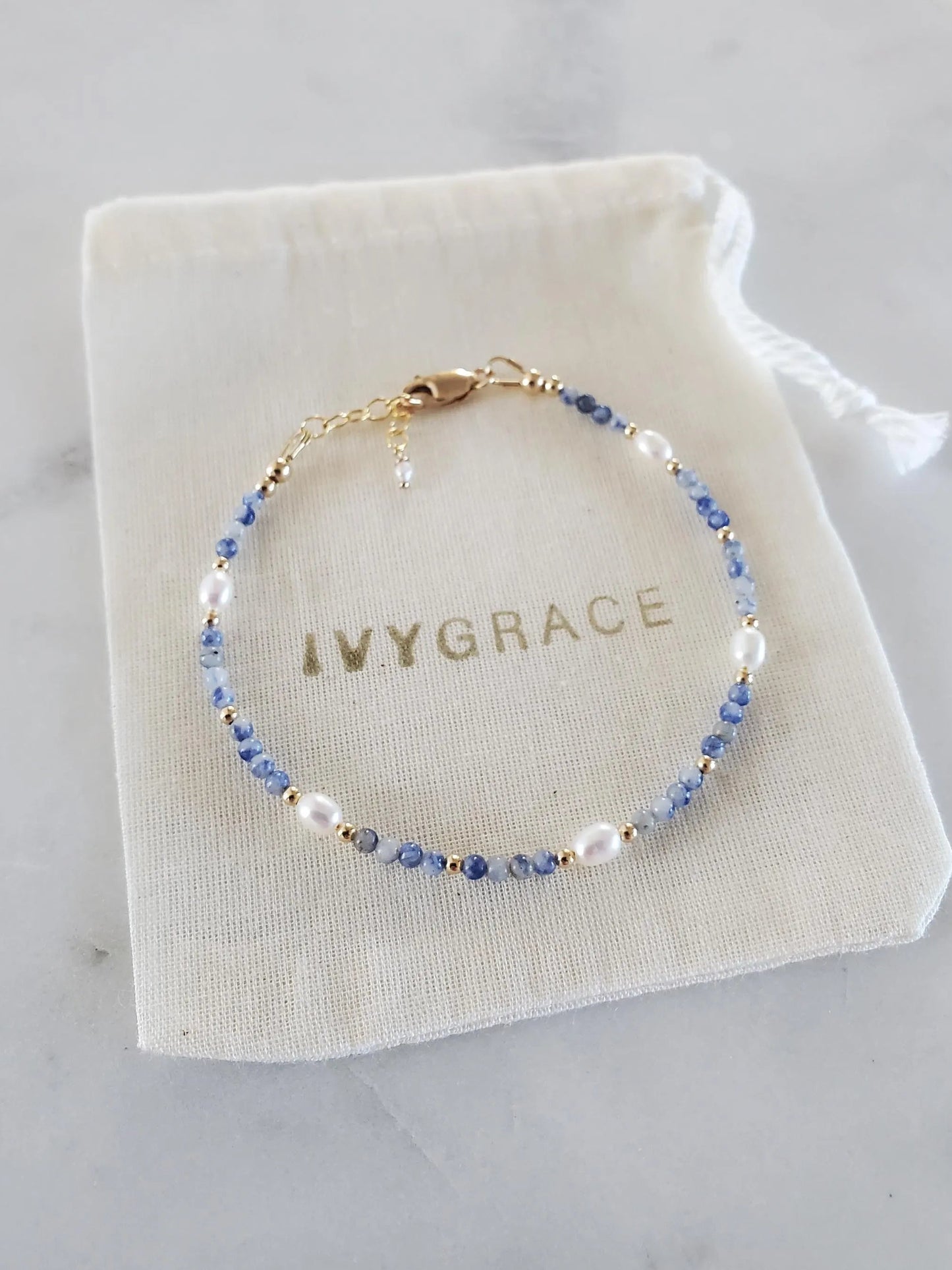 Beaded bracelet on a white drawstring bag with 'IVYGRACE' branding, on a light gray surface.
